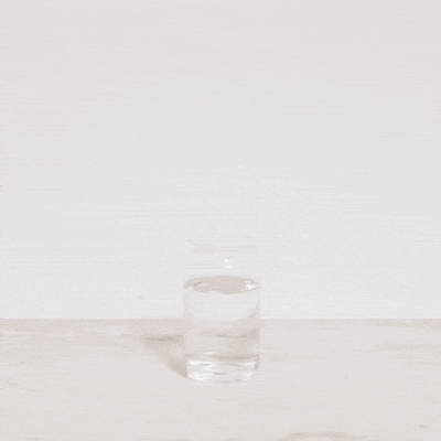 Mano vertiendo Supercalm en un vaso con agua